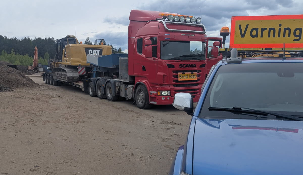 Tungatransport med Scania-dragbil och CAT-grävmaskin på trailer